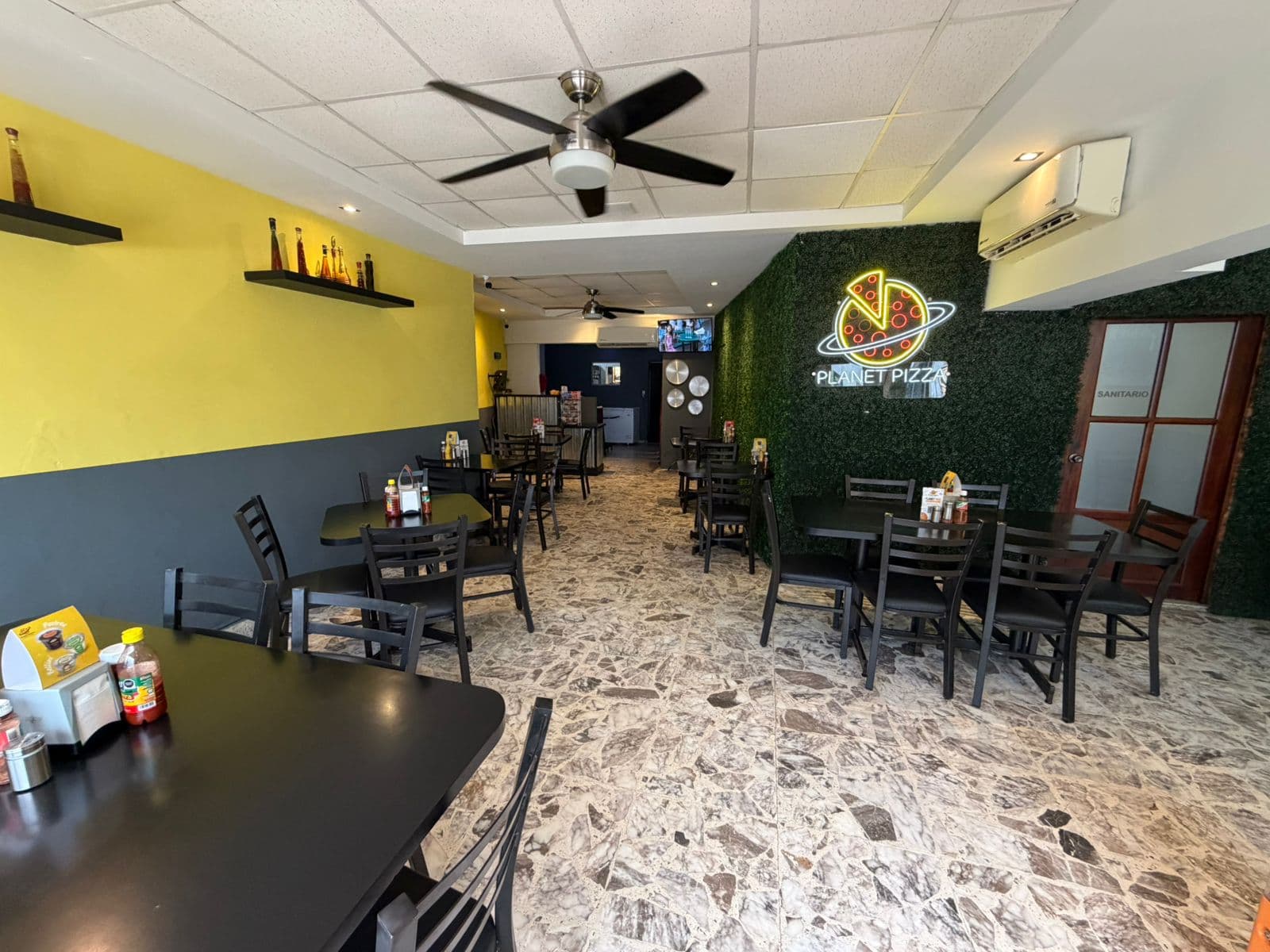El comedor, con el muro verde y el letrero de neón al fondo.