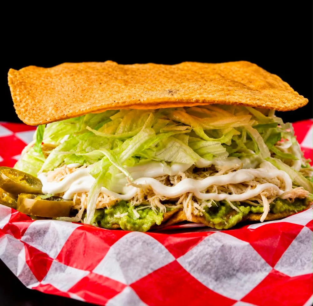 Tostada Siberia: pollo deshebrado, aguacate, lechuga y crema sobre tostada